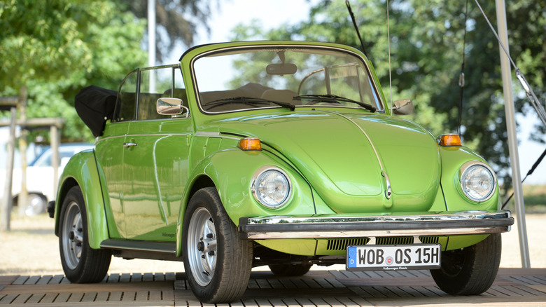 Green 1980 Volkswagen Beetle Cabriolet seen from front right on a platform at a vintage rally
