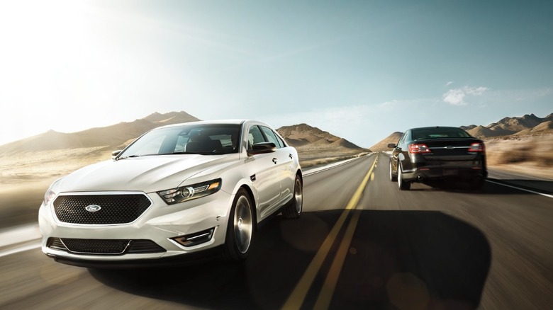 A pair of Ford Taurus on the road, one moving towards the camera and the other moving away.