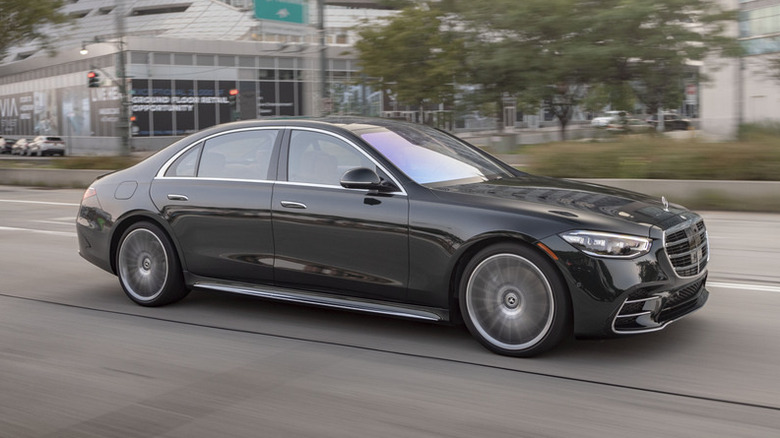 A black Mercedes S Class driving on a road.