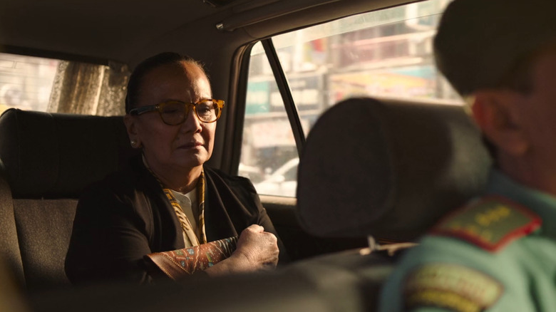 An Indonesian mycology professor rides silently in the back of a military vehicle after being urgently escorted by authorities in "The Last of Us."
