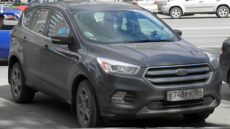A grey 2017 Ford Escape parked under the shade of a tree in public