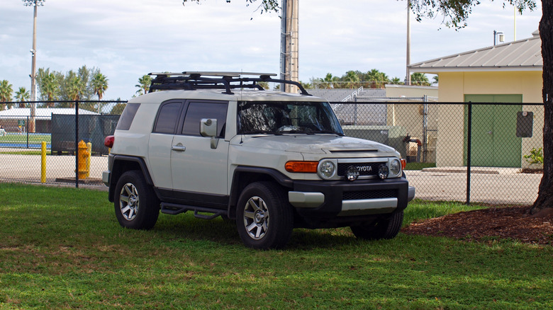 A White Toyota FJ Cruiser first generation parked on a lawn in the shade