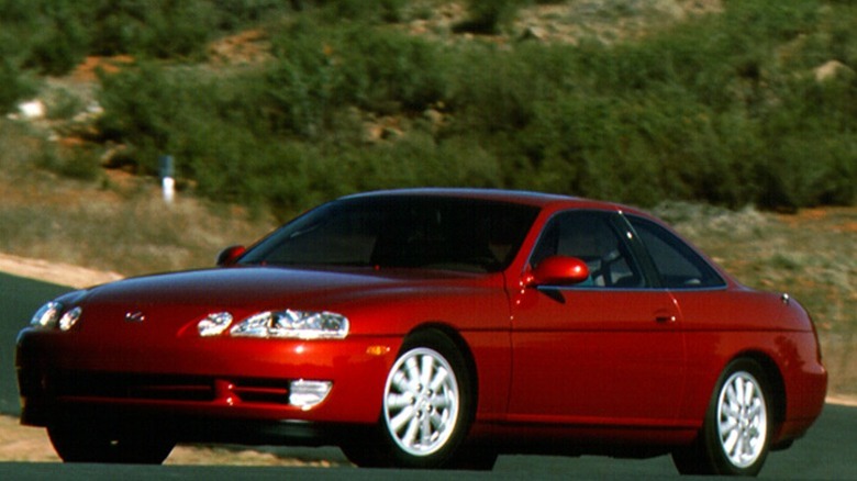 Deep red Lexus SC400 with a green hill view in the background