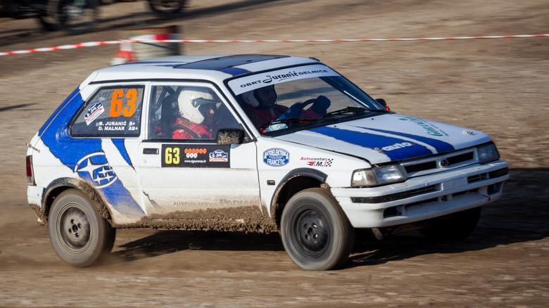 Front 3/4 shot of a rally modified 1988 Subaru Justy on a dirt road.