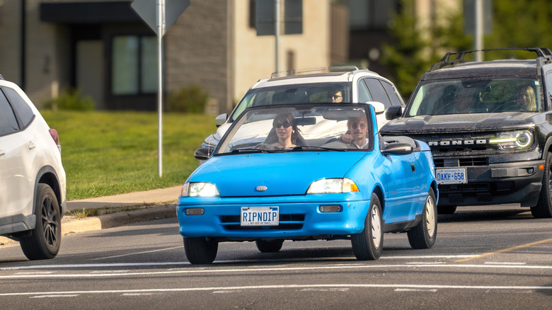 Front 3/4 shot of a blue 1993 Geo Metro convertible in traffic.
