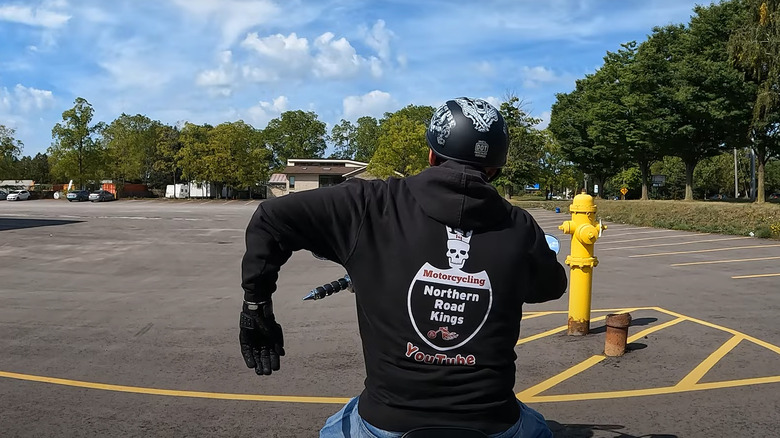 A biker wearing a branded jacket holding his left arm out at an angle