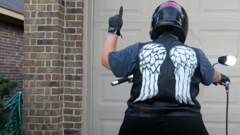 A biker wearing an Angel jacket showing the single file hand signal