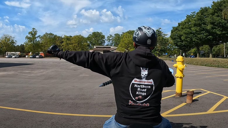 A biker wearing his club jacket demonstrating the turn left hand gesture