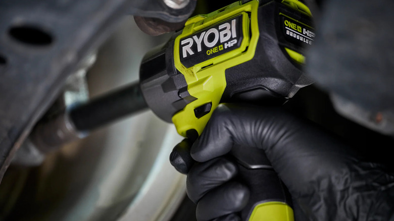 person using impact wrench under vehicle
