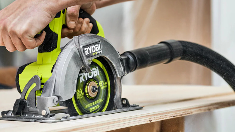 person using green circular saw on plywood