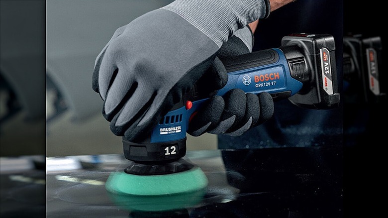 Using an orbital polisher on a metal surface.