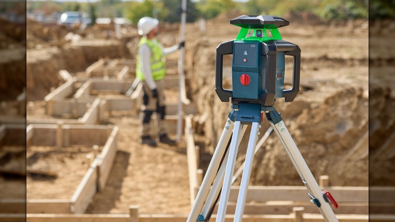 A rotary laser kit mounted on a tripod at a construction site.