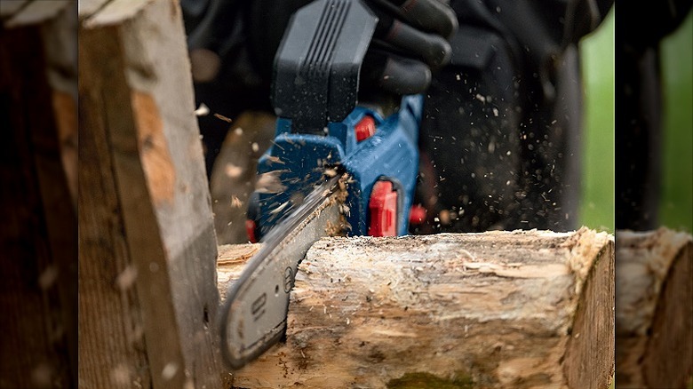 Cutting a wooden log using a pruning saw.