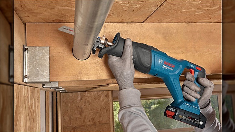 Cutting an overhead metal rod with a reciprocating saw.