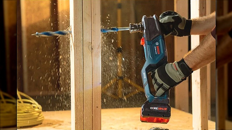 Using a right angle drill to drill through a piece of wood.