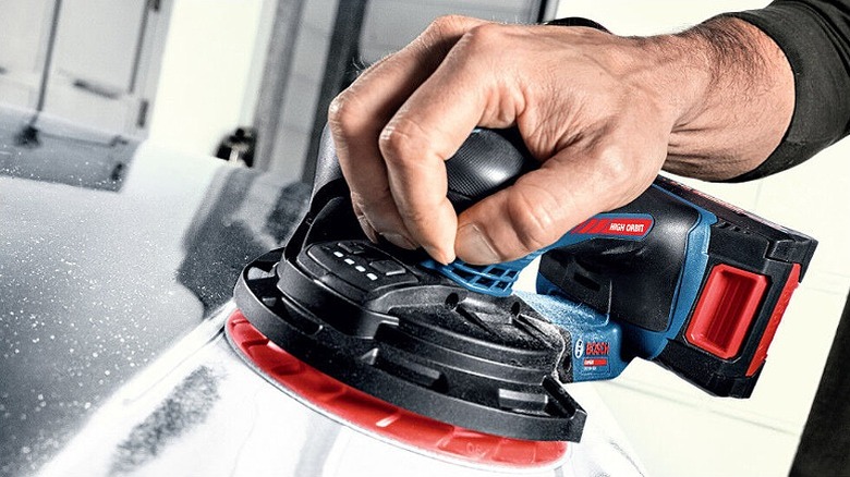 Using an orbit sander on a metal.