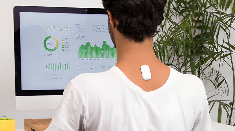 The upright posture device on man's neck as he works at computer