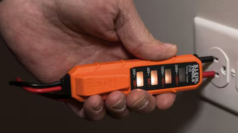 A person using the Klein electrical test kit with a wall outlet