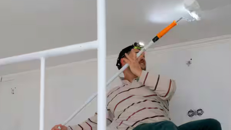 A person painting the ceiling while wearing the PowerSmith motion-sensing headlamp