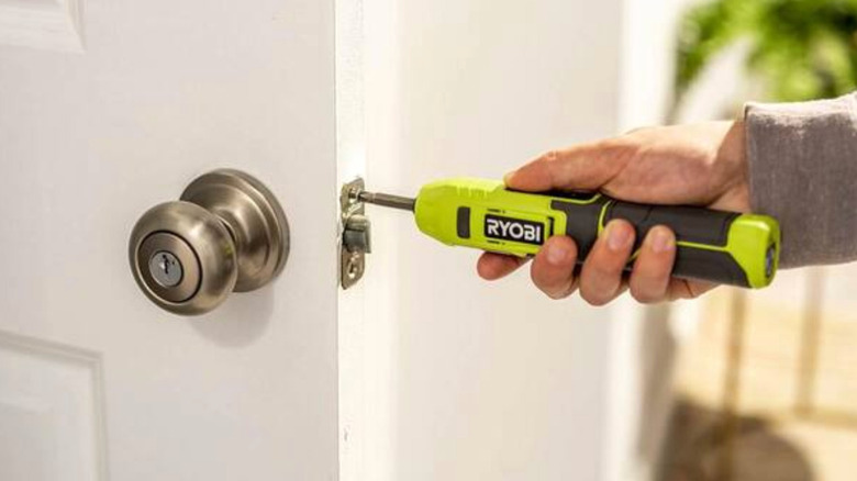 A Ryobi cordless screwdriver being used on a doorknob
