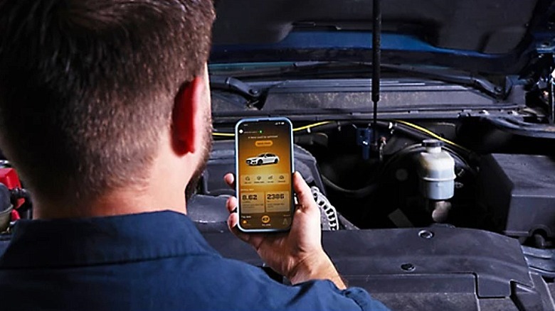 A mechanic assessing the vehicle diagnostics data on a smartphone.