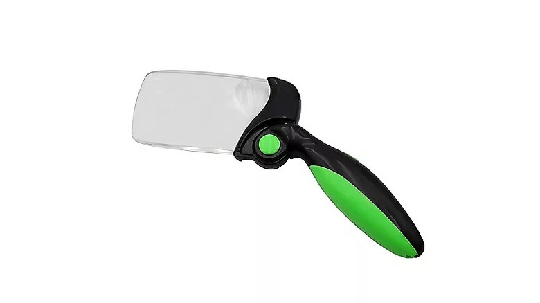 A black and green illuminated magnifier against a white background.
