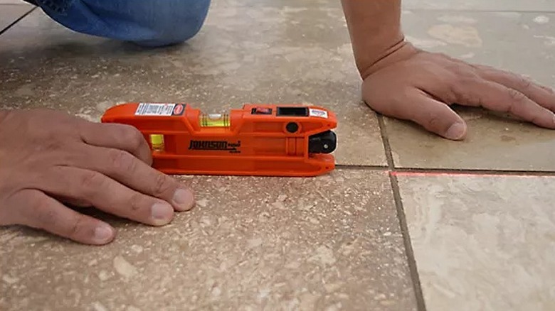 Using a torpedo laser level to assess tile placement.
