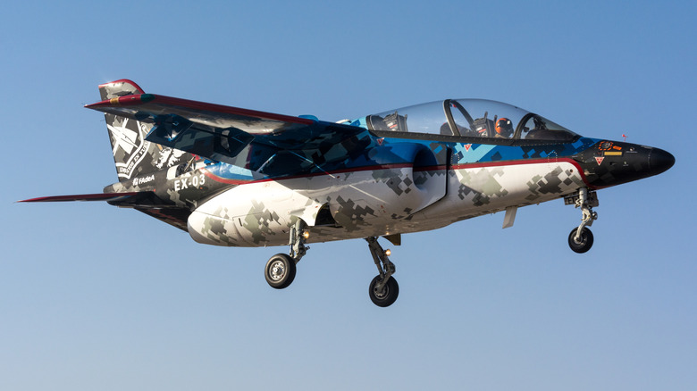 A camoflague-liveried FMA IA-63 Pampa III multirole light combat training aircraft against a clear sky.