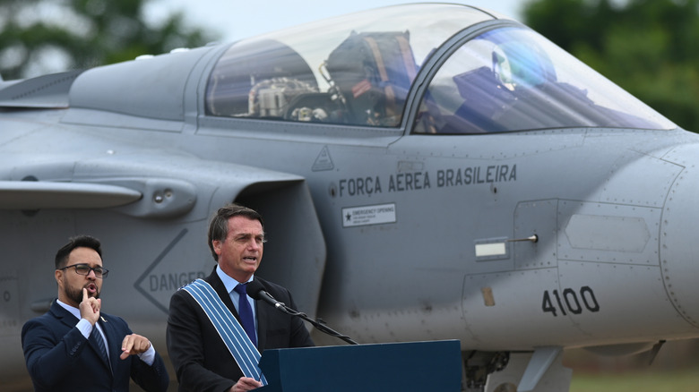 The president of Brazil standing next to a Swedish JAS-39E Gripen at a public event.