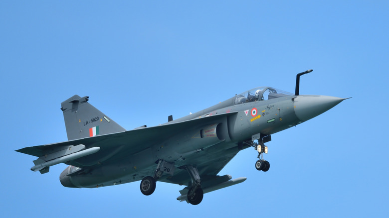 A Tejas light combat aircraft photographed against a clear blue sky.