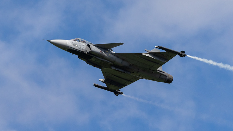 A SAAB JAS39-C Gripen taking off, right to left, from an airport.