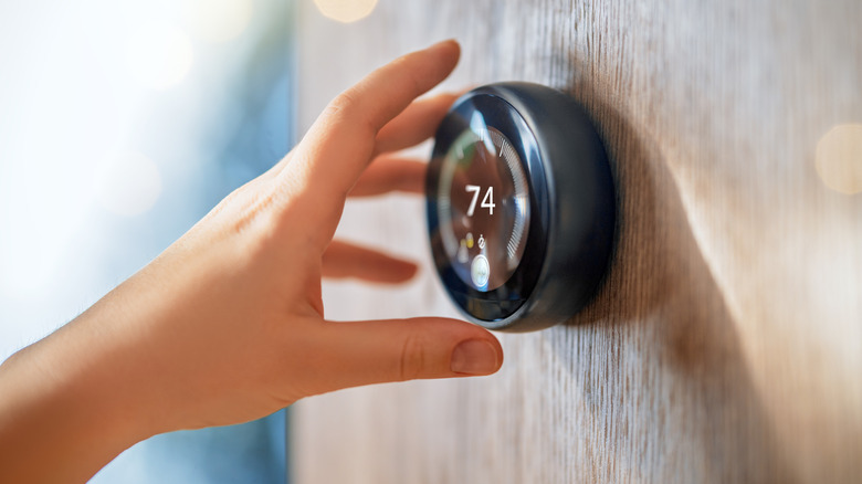 Person adjusting thermostat at home
