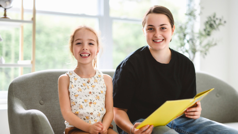 Young girl and teen babysitter reading together