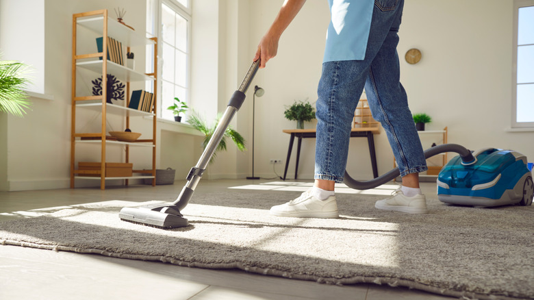 Cleaning service staffer vacuuming inside home