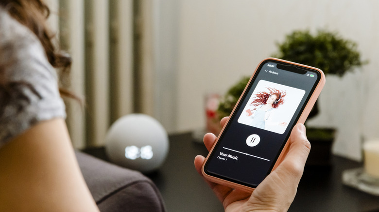 Woman playing music on Bluetooth speaker at home