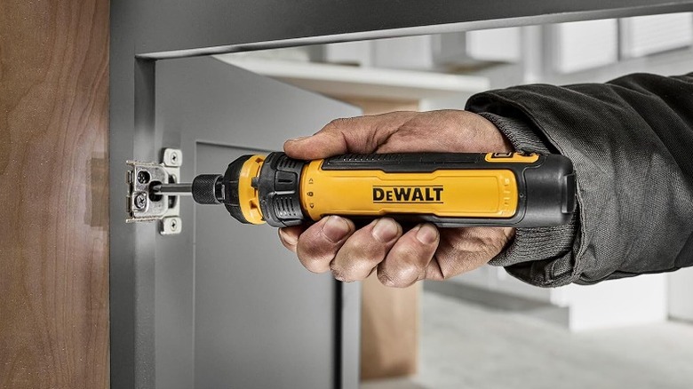 Using a cordless screwdriver on a cabinet lock.