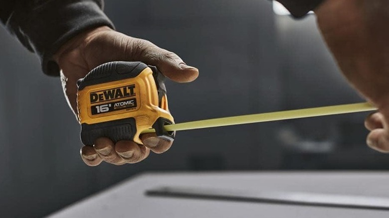 Man extending a DeWalt tape measure.