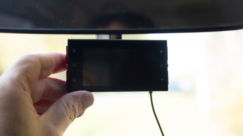 A radar detector mounted to the rear view mirror on a passenger car