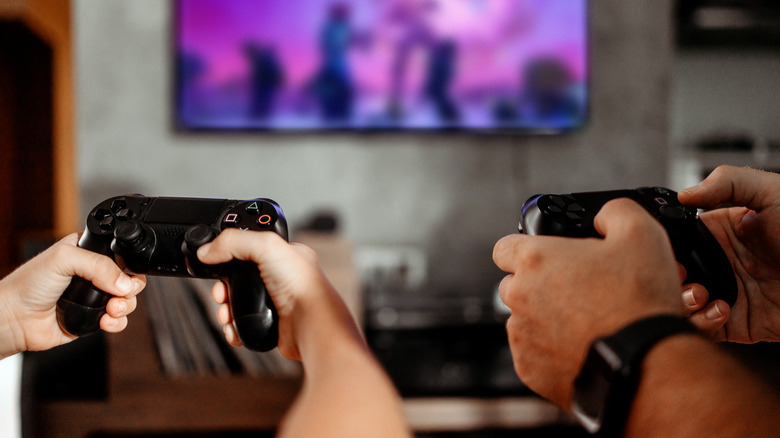 Two sets of hands holding video game controls
