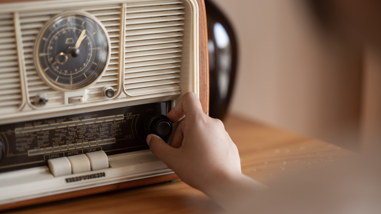Hand turning a dial on an old-fashioned radio
