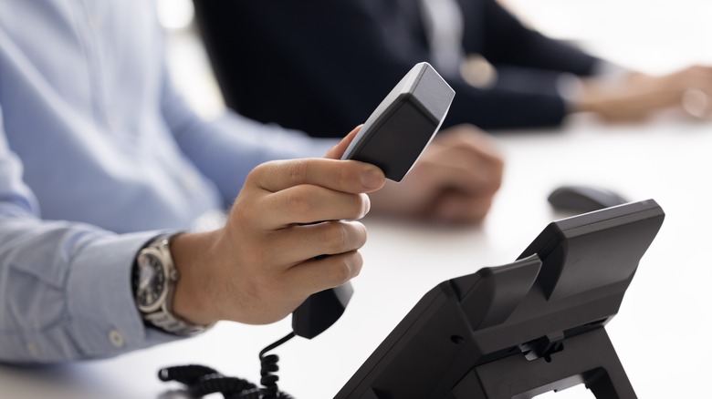 Person placing a phone receiver onto the main phone unit