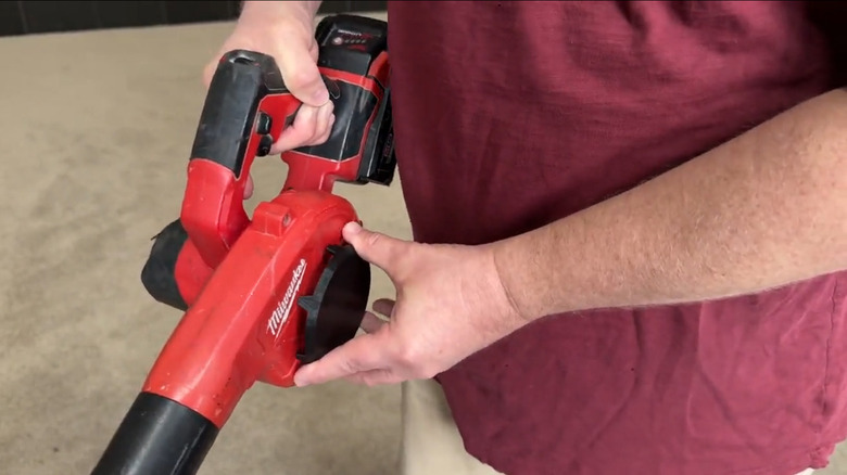 A person installs a 3D-printed air intake cover onto a Milwaukee M18 Compact Blower to prevent clothing from getting sucked into the intake.