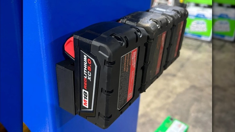 A magnetic battery holder holding Milwaukee M18 batteries on a vertical metal surface.