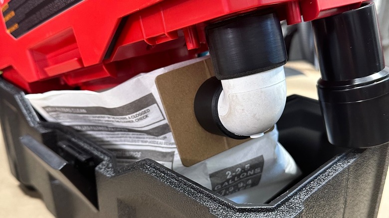 A Milwaukee M18 two-gallon vacuum fitted with a 3D-printed adapter and a connected vacuum bag.
