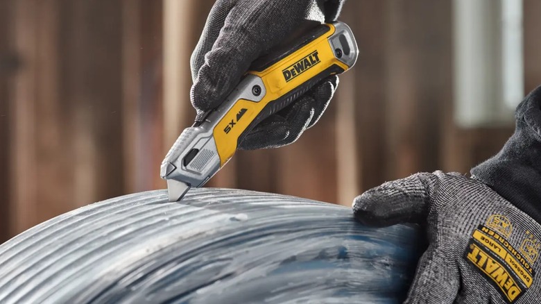 cutting open a roll of tubing with DeWalt knife