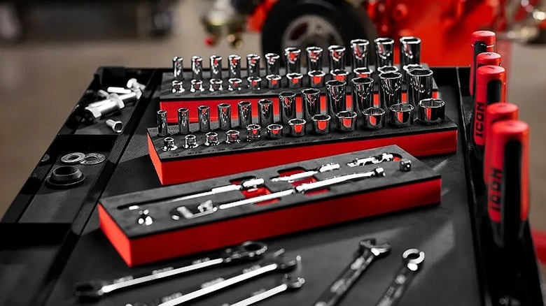 Several sockers and hand tools organized in separate racks placed on a table.