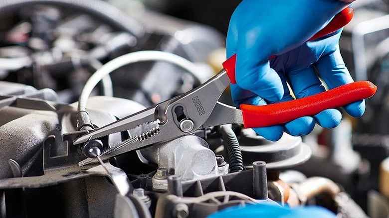 Gloved hands working on a vehicle with Icon pliers.