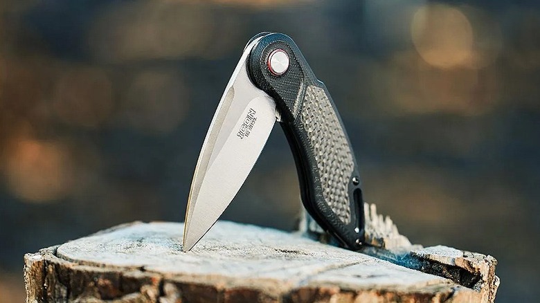 A drop point knife placed on a piece of wood.