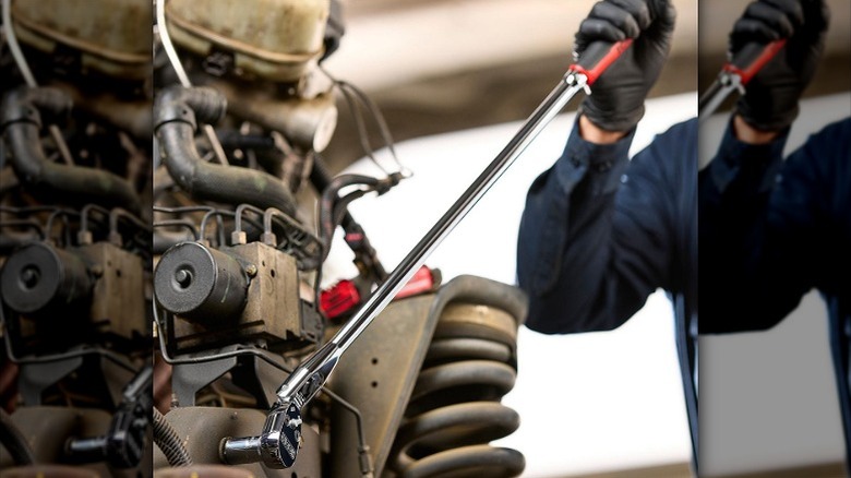 Professional working with a long ratchet on machinery.