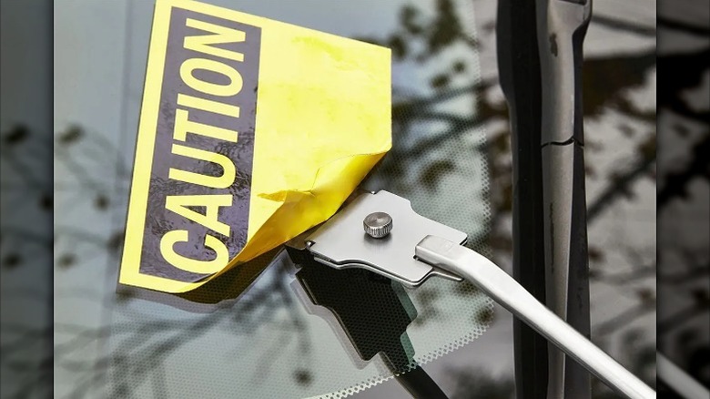 Removing an old "caution" sticker using a scraper.